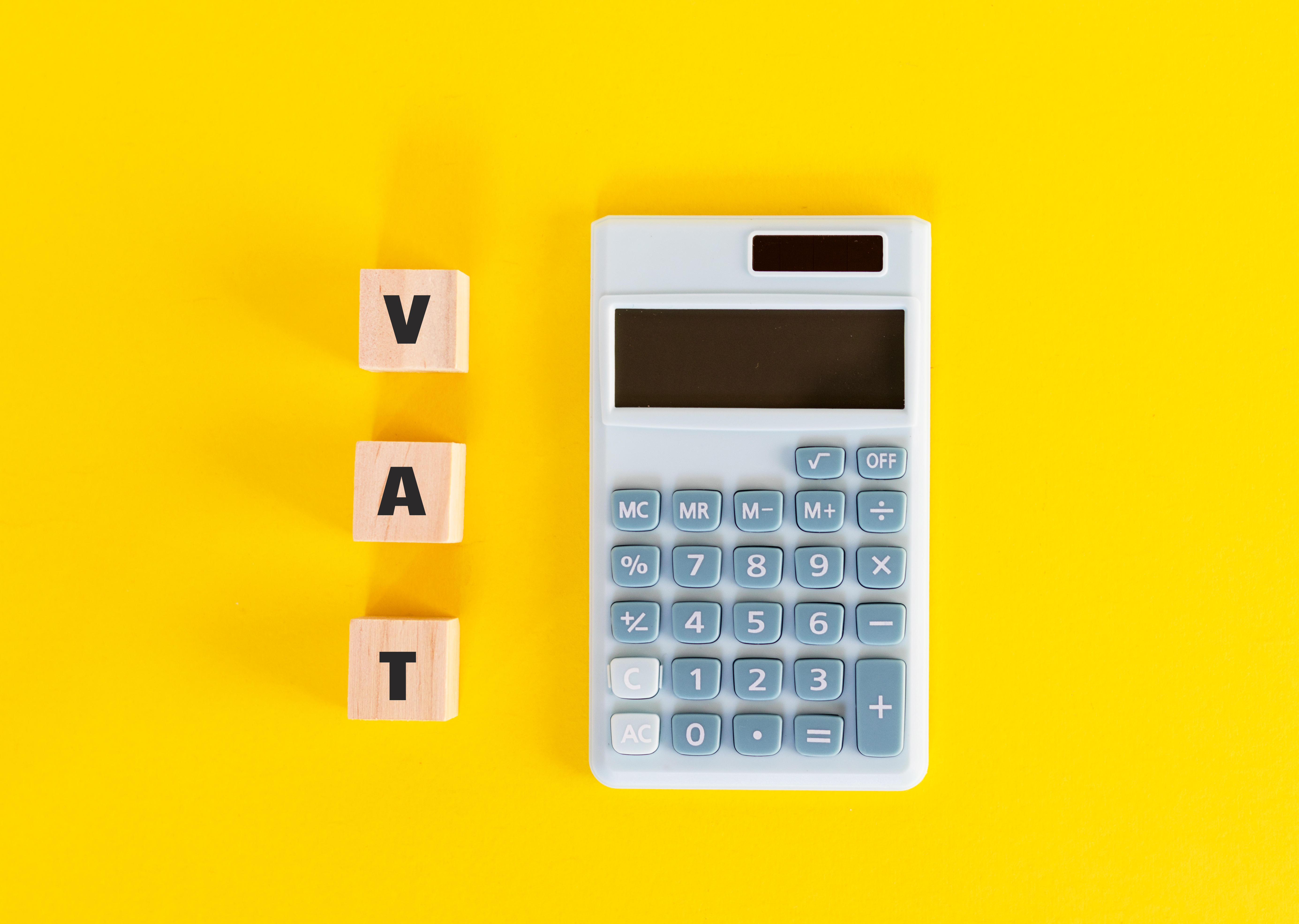 mini-calculator-wooden-cubes-with-text-vat-yellow-background-value-added-tax-finance-money-flat-lay-top-view